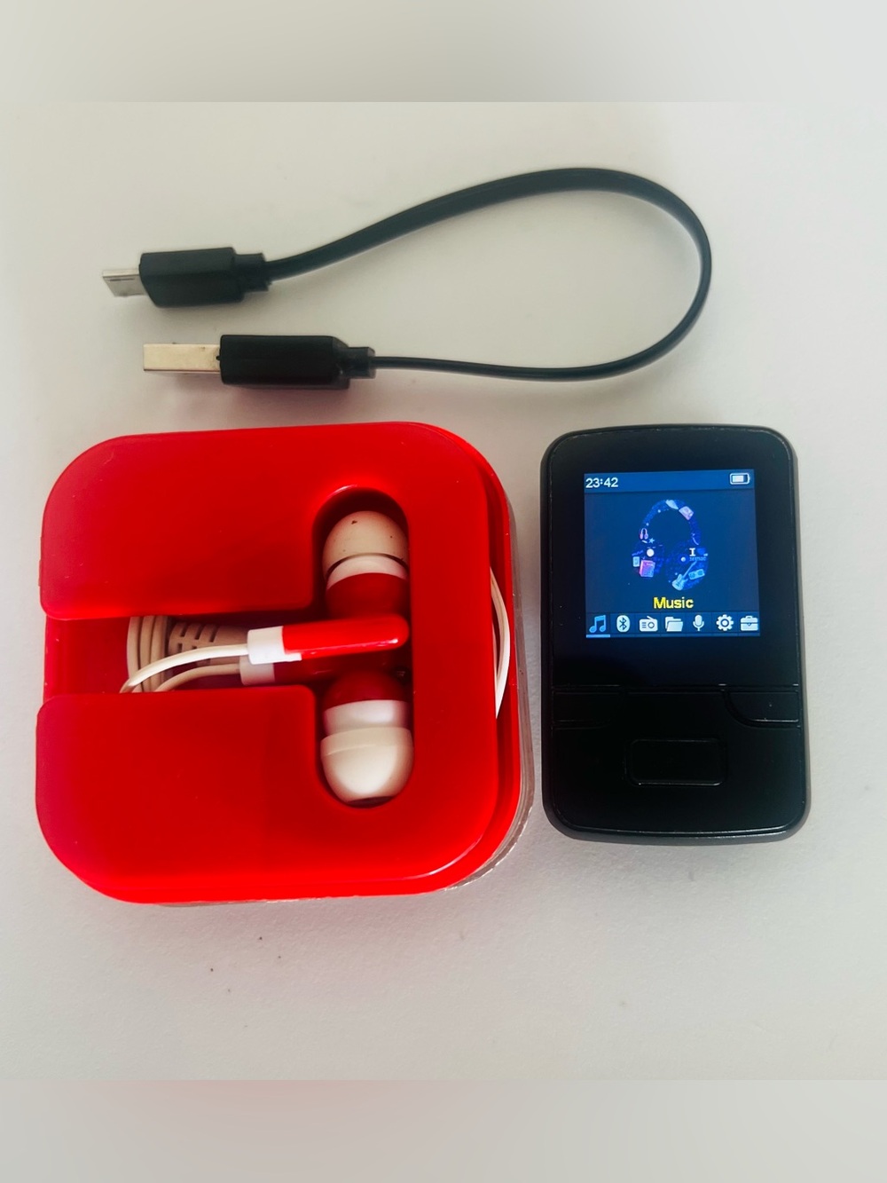 Compact Black MP3 Player Claps with Red Earbud Case and White Earphones working